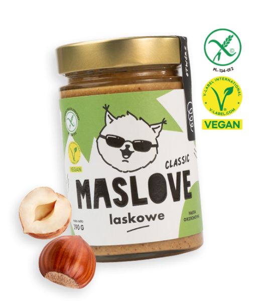 Szklany słoik o pojemności 290 g z masłem z orzechów laskowych od Maslove w konsystencji klasycznej. Ozdobione etykietą z nazwą produktu oraz rysunkową wiewiórką w okularach. Produkt objęty certyfikatem wegańskim i bezglutenowym. Przy słoiku widnieje obrazem orzechów laskowych.